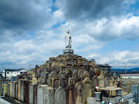 JAPAN, NARA - APRIL 12, 2018: A Japanese cemetary in Nara with a buddha statue at the top of a pyramid of many tombstones.のeditorial素材