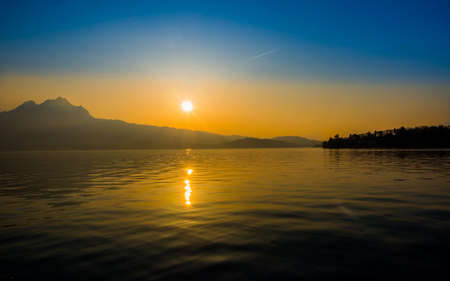 Sun reflection while setting over a lake in Switzerlandの写真素材