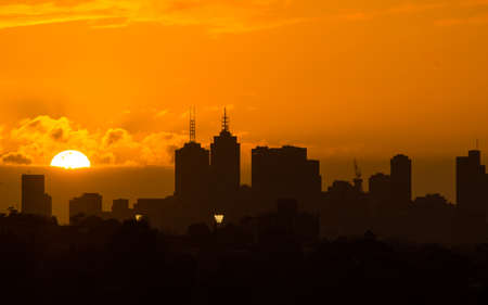Big golden sun setting behind Melbourne city skylineの写真素材