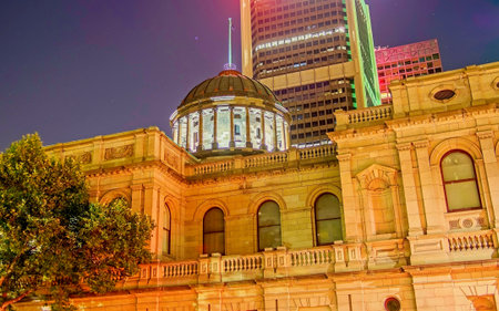 A night view of the historic Supreme Court of Victoria building in Melbourne. The image features the illuminated classic copper dome and sandstone facade contrasting against a modern high-rise office tower in the background.の写真素材
