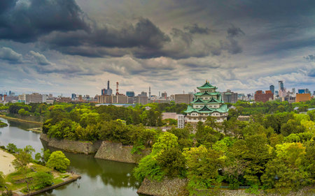 NAGOYA, JAPAN - APRIL 28, 2019: An aerial view of the Nagoya Castle complex, featuring the Main Keep, moat, and defensive stone walls. The historic site is surrounded by the modern urban buildings of downtown Nagoya under a dramatic sky.のeditorial素材