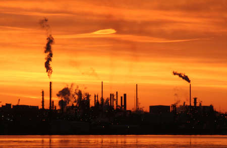 A silhouette of a refinery with a bright orange sky, taken before sunriseの写真素材