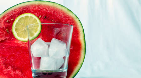 A glass with ice and a slice of lemonの写真素材