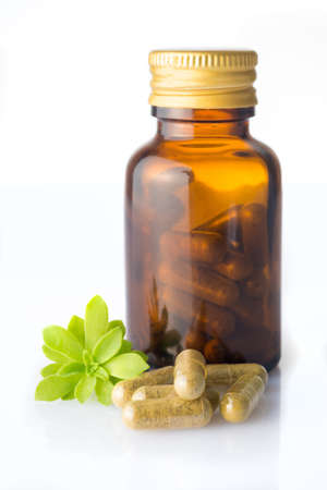 Bottle of homeopatic pills with some pills and herb leafの写真素材
