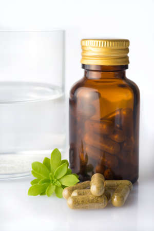 Bottle of homeopatic pills with some pills and herb leaf and water glassの写真素材