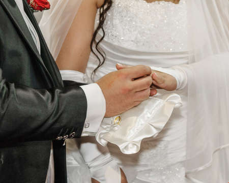 A groom putting gold ring on bride finger