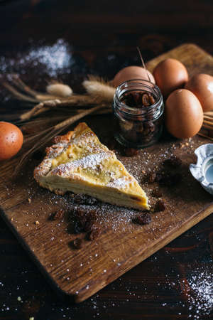 Traditional italian cake with ricotta cheese and raisin, eggs, jar and powdered sugar on wooden background, selective focusの写真素材