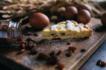 Traditional italian cake with ricotta cheese and raisin, eggs, jar and powdered sugar on wooden background, selective focusの写真素材