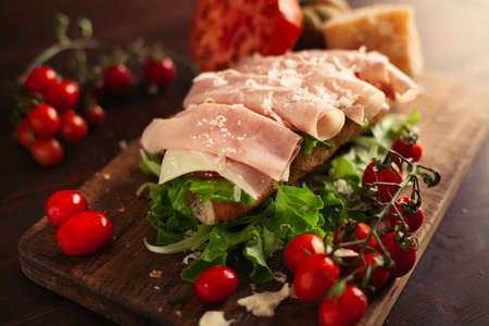 A view of a sandwich with a salad, cheese and ham on a wooden tableの写真素材