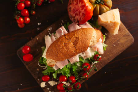 A view of a sandwich with a salad, cheese and ham on a wooden tableの写真素材