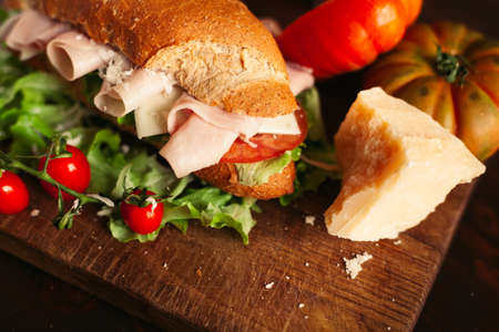 A view of a sandwich with a salad, cheese and ham on a wooden tableの写真素材