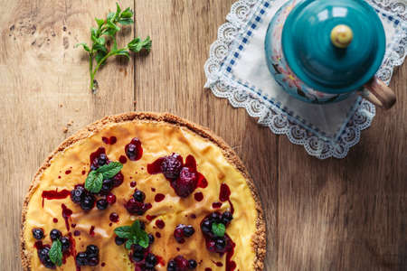 A side view of a cheesecake on a wooden floor with hazelnutsの写真素材
