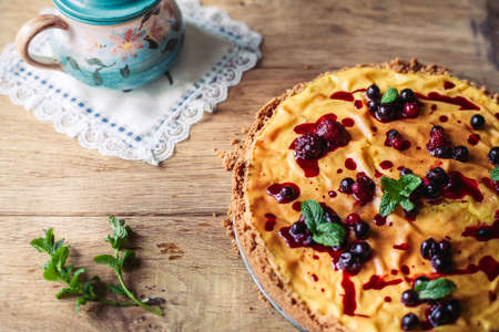 A side view of a cheesecake on a wooden floor with hazelnutsの写真素材