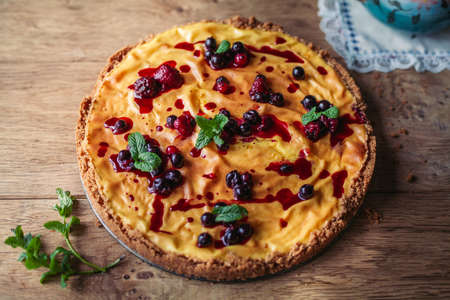 A side view of a cheesecake on a wooden floor with hazelnutsの写真素材