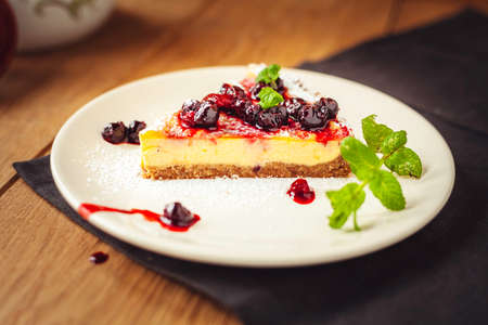 A side view of a cheesecake on a wooden floor with hazelnutsの写真素材