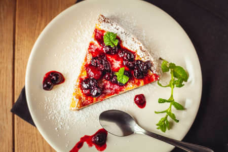 A side view of a cheesecake on a wooden floor with hazelnutsの写真素材