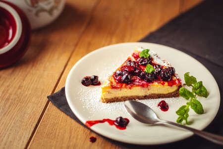 A side view of a cheesecake on a wooden floor with hazelnutsの写真素材