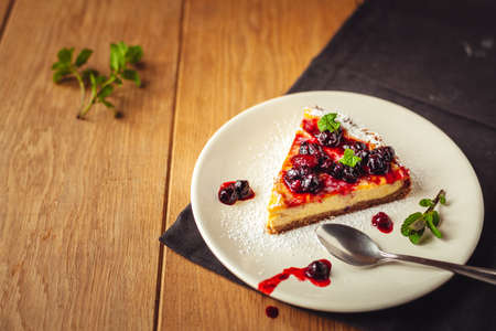 A side view of a cheesecake on a wooden floor with hazelnutsの写真素材