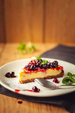 A side view of a cheesecake on a wooden floor with hazelnutsの写真素材
