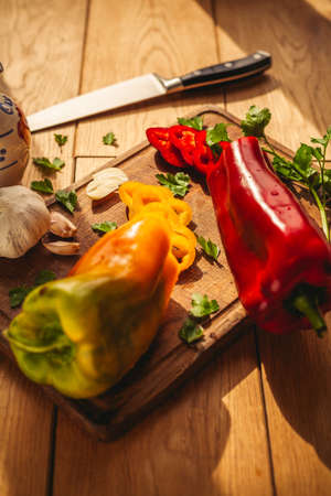 A view of two peppers on the chopping board with some ingredients around them: garlic, parsley, oilの写真素材
