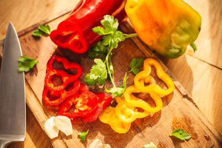 A view of two peppers on the chopping board with some ingredients around them: garlic, parsley, oilの写真素材