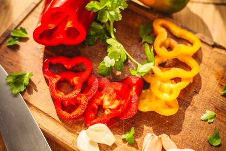 A view of two peppers on the chopping board with some ingredients around them: garlic, parsley, oilの写真素材