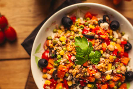 A view of a spelled dish on wooden background with some ingredients around: carrots, peppers, tomatos, parsley and oilの写真素材