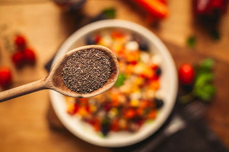 A view of a spelled dish on wooden background with some ingredients around: carrots, peppers, tomatos, parsley and oilの写真素材