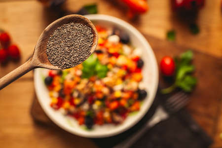 A view of a spelled dish on wooden background with some ingredients around: carrots, peppers, tomatos, parsley and oilの写真素材