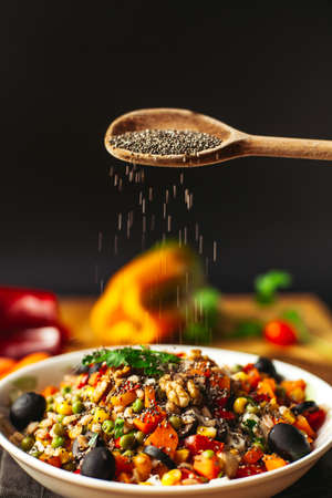 A view of a spelled dish on wooden background with some ingredients around: carrots, peppers, tomatos, parsley and oilの写真素材