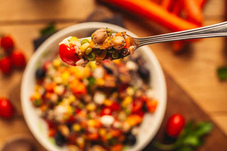 A view of a spelled dish on wooden background with some ingredients around: carrots, peppers, tomatos, parsley and oilの写真素材