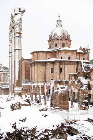 a beautiful view of snowy Roman Forums and Church of the Saints Luca and Martina under the snowの写真素材