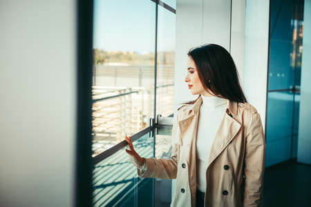 Girl is looking out of the window from a modern buildingの写真素材