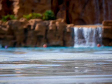 the water of the swimming pool into an acquapark in the south of italy with an artificial waterfall that comes out from a rocky wallの写真素材