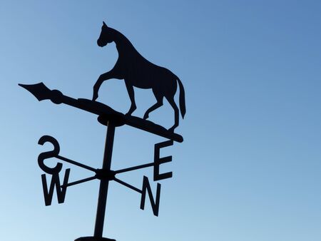 an horse weathervane on a blue sky backgroundの写真素材