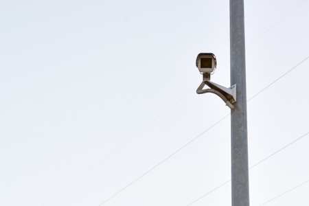 surveillance camera fixed on a pole on a cloudy sky background