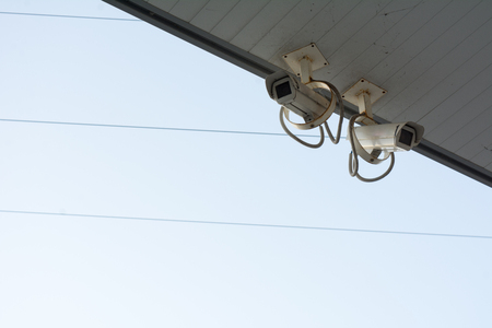 surveillance cameras fixed under a shelter on a cyan sky backgroundの写真素材