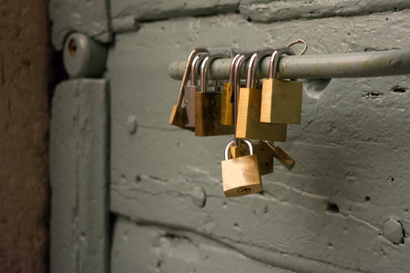 close up of some padlocks hanged on a handle of an old grey doorの写真素材