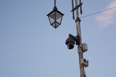surveillance cameras on a street lamp on cloudy sky background