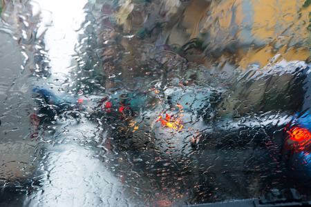 Raindrops On The Windshield Of A Car During A Thunderstorm In A City With Automobile Traffic As A Blurry Backgroundの写真素材