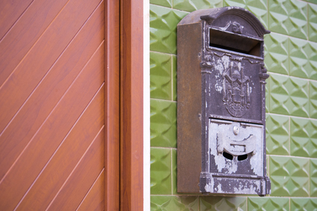 Old Grey Mailbox on a Green Wall Near a Brown New Doorの写真素材