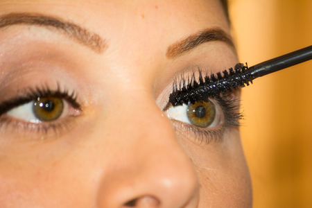 Close Up of Woman Stretching Skin Using Mascara on Blur Backgroundの写真素材