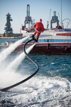 Vertical View of Santa Claus on Flyboard on Blur Background. Taranto, Italyの写真素材