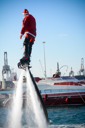 Vertical View of Santa Claus Flying on Flyboard on Blur Background. Taranto, Italyの写真素材