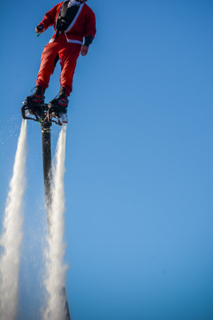 Vertical View of Santa Claus on Flyboard on Blue Sky Backgroundのeditorial素材