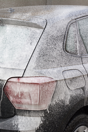 Man Spraying Active Foam During Car Wahing on Blurred Backgorundの写真素材