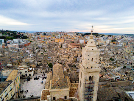 Aerial Panoramic View of the Belltower of the Cathedral of St. Maria La Bruna on Cloudy Sky at Sunset. Matera, Italyの写真素材