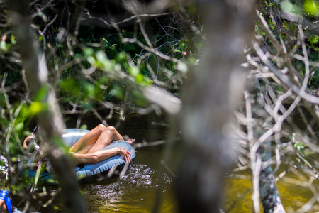 Man on Floating Donut in a River on Blur Forest Foreground at Turkey Creek, Niceville, Floridaの写真素材