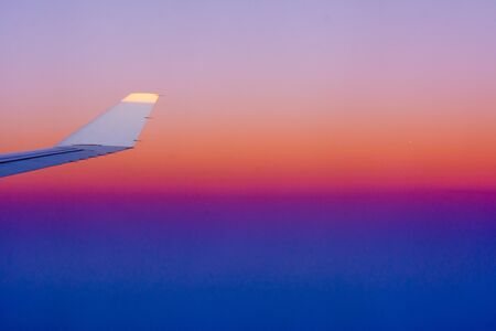 Close Up of Wing of an Airplane in flight on Colored Clear Sky Background