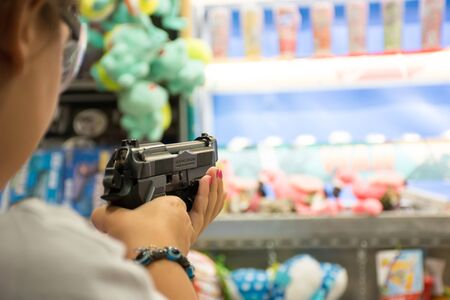 Close Up of Hand of a Young Girl Shooting with an Air Pistol at Luna Park on Blur Backgroundの写真素材